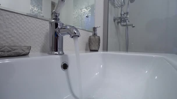 Ανοιχτό chrome βρύση νιπτήρα. Το νερό ρέει από τη βρύση στο μοντέρνο μπάνιο - Πλάνα, βίντεο