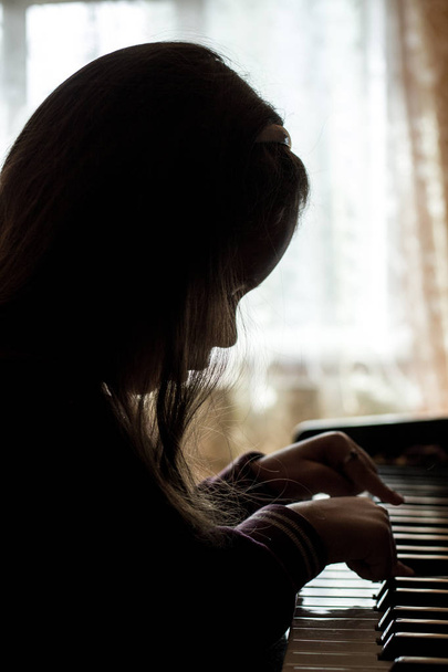 silhouette of a girl playing the piano - Valokuva, kuva