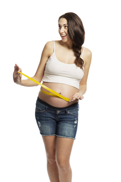 A pregnant woman measures the abdominal circumference. Isolated on a white background. - Fotoğraf, Görsel