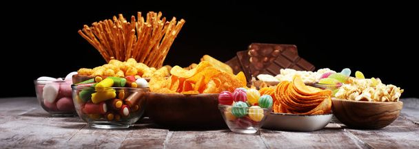 Petiscos salgados. Pretzels, batatas fritas, biscoitos em tigelas de madeira na mesa
 - Foto, Imagem