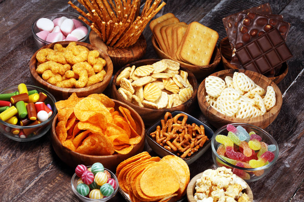 Salty snacks. Pretzels, chips, crackers in wooden bowls on table - Photo, Image