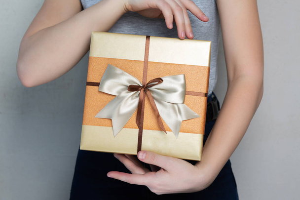 Caucasian young girl wearing t shirt holding gift box with a bow - Photo, image