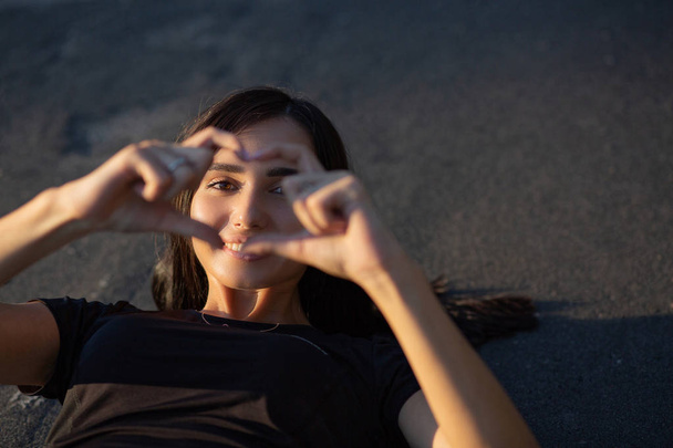 Lachende atletische vrouw maken hartsymbool van haar vingers op t - Foto, afbeelding
