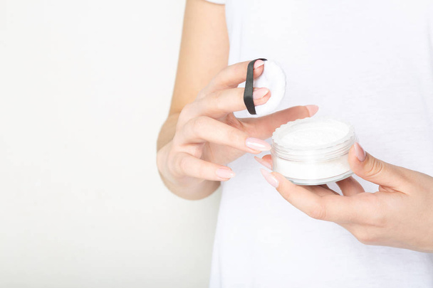 Mujer sosteniendo polvo cosmético transparente sobre un fondo blanco
 - Foto, imagen