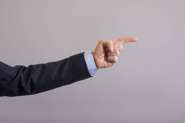 The businessman's hand points with his index finger at the gray background. - Photo, Image