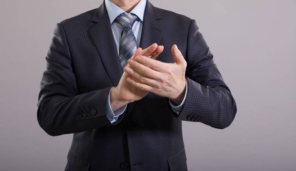 Businessman clapping his hands on a gray background. - Foto, Imagen