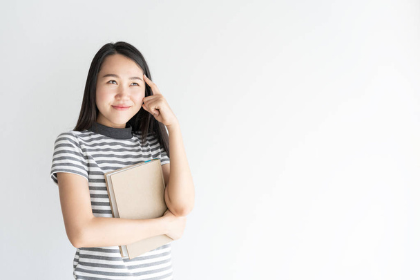 Portrait of asian woman thinking and holding notebook  on white background and copy space - Φωτογραφία, εικόνα