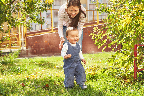 молодая мама играет с ребенком. Мама и сын гуляют в парке
 - Фото, изображение