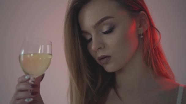 The girl drinks white wine, close-up and red backlight. . Slow motion 60fps - Záběry, video