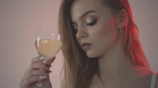 The girl drinks white wine, close-up and red backlight. . Slow motion 60fps - Кадры, видео