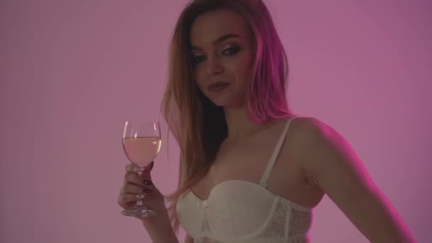 The girl drinks white wine, close-up and red backlight. Slow motion. - Materiał filmowy, wideo