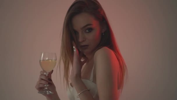 The girl drinks white wine, close-up and red backlight. . Slow motion 60fps - Materiał filmowy, wideo