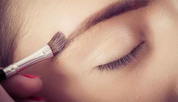 Professionele make-up kunstenaar verbetert de wenkbrauwen op de vrouwelijke f - Foto, afbeelding