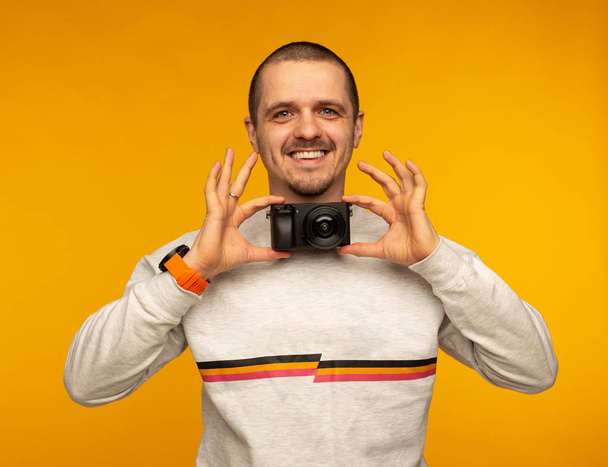 Φωτογράφος άνθρωπος κρατάει την κάμερα ως παπιγιόν και χαμογελαστός - Φωτογραφία, εικόνα