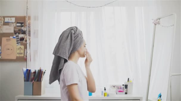 Mulher limpa a pele do rosto com uma almofada de algodão na sala
 - Filmagem, Vídeo