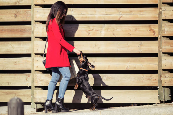 Cool young beautiful woman feeding her sweet dog playfuly in the street. - Foto, Bild