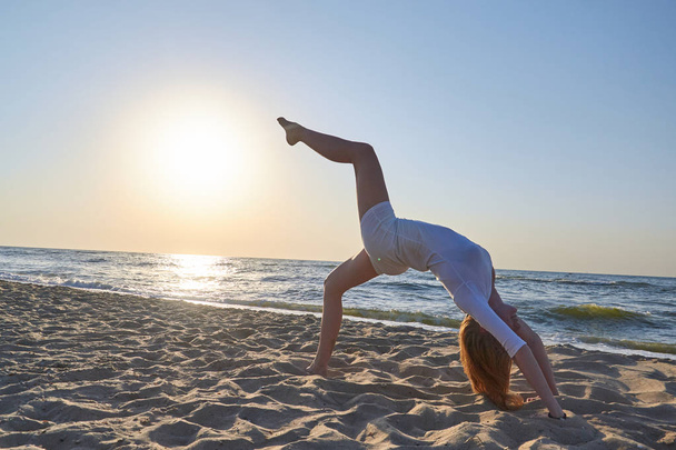 schöne Frau macht Yoga Asana am Strand mit defokussiertem Hintergrund. - Foto, Bild