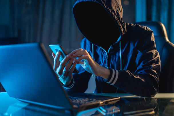 匿名のハッカー プログラマーは、暗闇の中でシステムをハックするのにラップトップを使用します。サイバー犯罪とハッキングのデータベースの概念 - 写真・画像