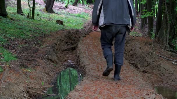 Man goes along muddy forest path - Footage, Video