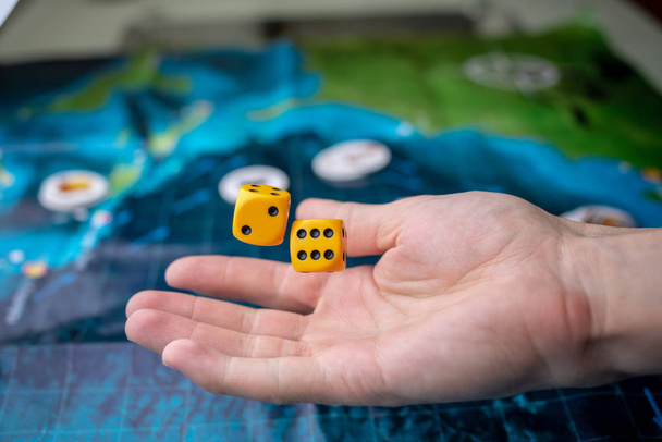 Hand throws yellow dice on the playing field. Gaming moments in dynamics. Concept of Board games. - Photo, Image