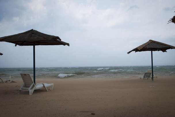 Storm op zee met onweerslucht. Strand parasols en ligbedden op het strand. - Foto, afbeelding