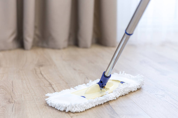 Modern white mop cleaning a wooden floor - Фото, изображение