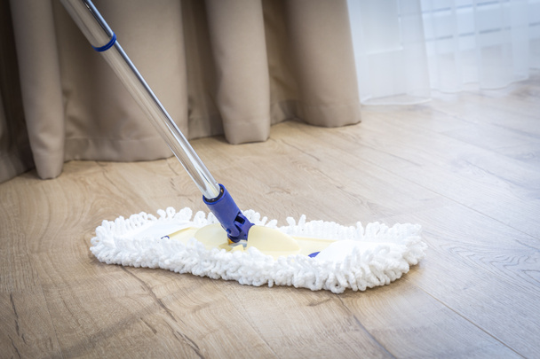 Modern white mop cleaning a wooden floor - Fotó, kép