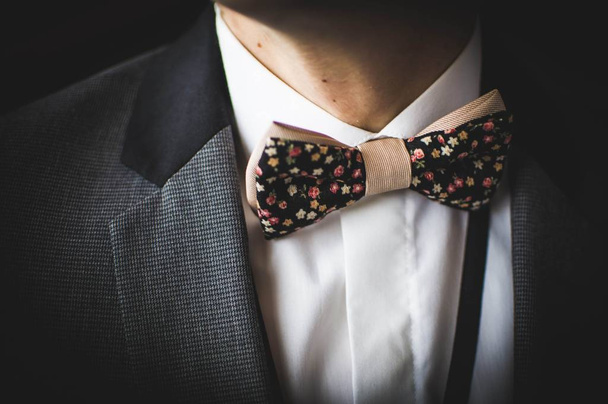 Красива коричнева краватка з дрібними барвистими квітами на білій сорочці та сірому піджаку
 - Фото, зображення