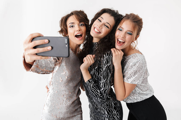 Young happy women friends posing isolated over white wall background. on a party. - 写真・画像