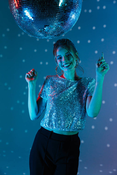 Young happy woman posing isolated with disco ball lights. - 写真・画像