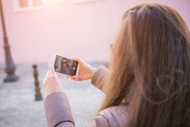 Pleased brunette woman in autumn clothes making selfie on smartphone - Foto, Bild