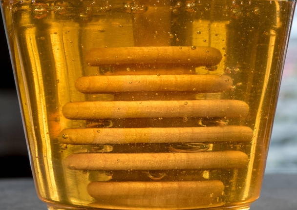 Ковш с медом, погруженный в стакан с медом
 - Фото, изображение