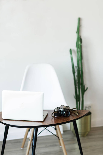 Minimaalinen työpaikka kotona tietokone, valokamera ja kaktus
 - Valokuva, kuva