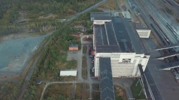 Vista aérea de un enorme edificio industrial gris cerca de vías férreas y terrenos baldíos, rodeado de bosques. Zona industrial desde arriba
. - Imágenes, Vídeo