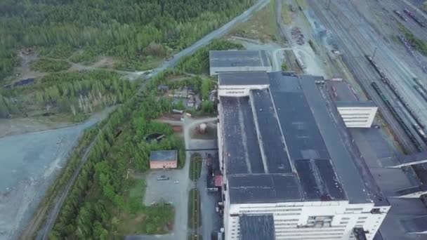 Luchtfoto van enorme grijs industrieel gebouw in de buurt van trein- en afval grond, omringd door bos. Industriële zone van boven. - Video
