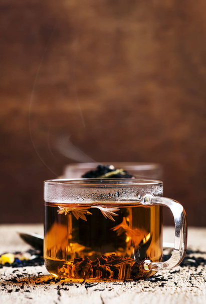 Dry Ceylon black tea with cornflower blue flowers and dried fruit, vintage wooden kitchen table background, close up, selective focus - Valokuva, kuva