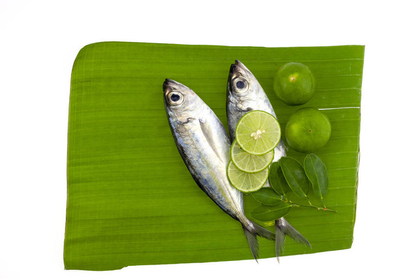 рыба с лимоном и листочками на фоне банановых листьев
 - Фото, изображение