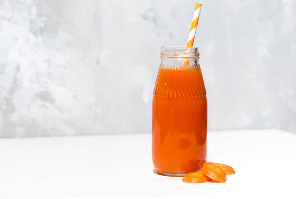 fresh carrot juice in a bottle on white background, closeup - Foto, afbeelding
