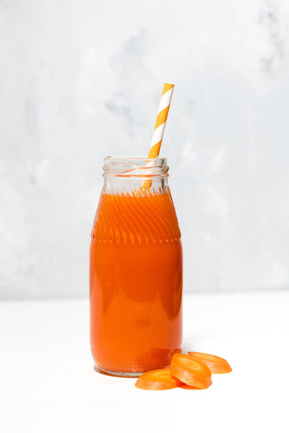 fresh carrot juice in a bottle on white background, vertical - Фото, изображение