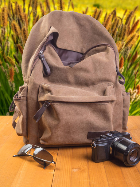 Travel concept. Backpack, camera and glasses on a wooden background - Фото, изображение