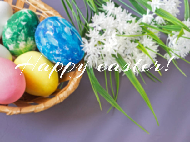 Easter eggs in a basket on a gray background and blooming white flowers - Foto, immagini