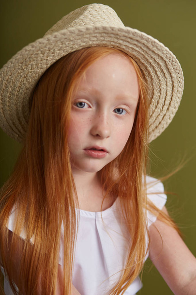 Young red-haired girl in a straw hat with long beautiful hair an - Φωτογραφία, εικόνα