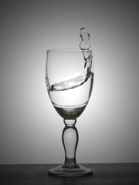 Spray liquid (clear water, red wine) from a glass goblet. - Fotoğraf, Görsel