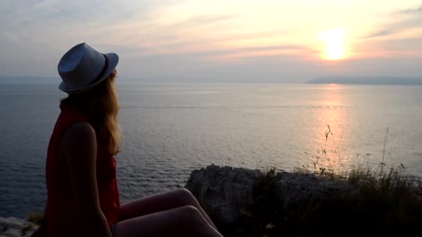 Chica viendo la puesta de sol sobre el mar pensando en el significado de la vida
 - Metraje, vídeo