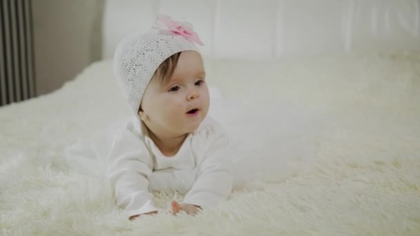 Beautiful little girl is lying on the white bed. - Imágenes, Vídeo