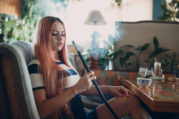 Fiatal gyönyörű női fekete fehér csíkos ruha dohányzás vízipipa. Dohányzás shisha vízipipa koncepció. - Fotó, kép