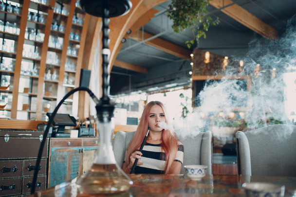 Fiatal gyönyörű női dohányzás vízipipa. Dohányzás shisha vízipipa café koncepció. - Fotó, kép