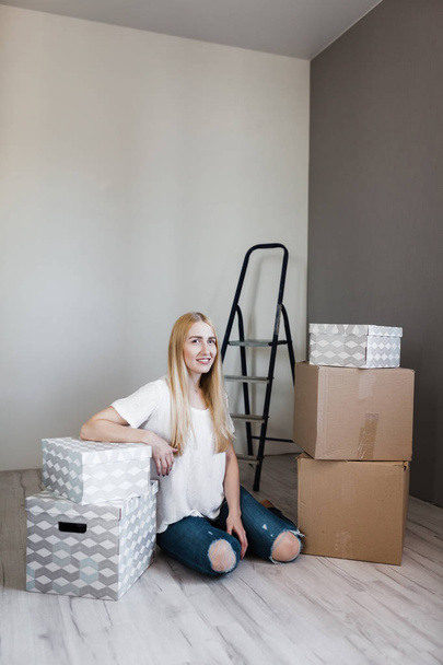 Young woman moving into new apartment holding cardboard boxes with belongings.Photo of young blonde with cardboard box. - Valokuva, kuva