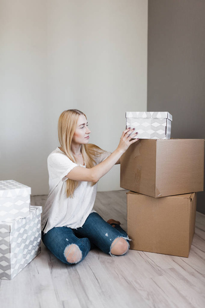 young blonde smile woman surrounded cardboard boxes sitting on floor after relocation - Photo, image
