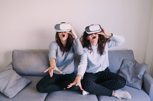 Two friends try to reach something while they enjoy virtual reality glasses - Foto, immagini